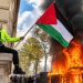 Protester with Palestinian Flag Amid Flames